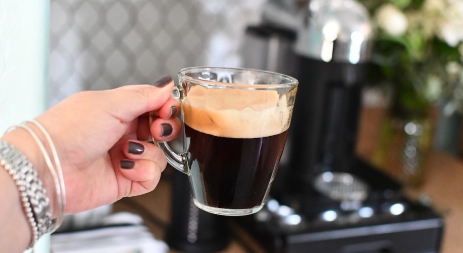 holding a glass mug of coffee