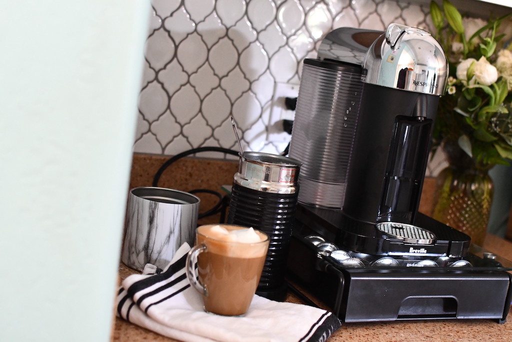 Nespresso breville machine with cup of coffee on counter 