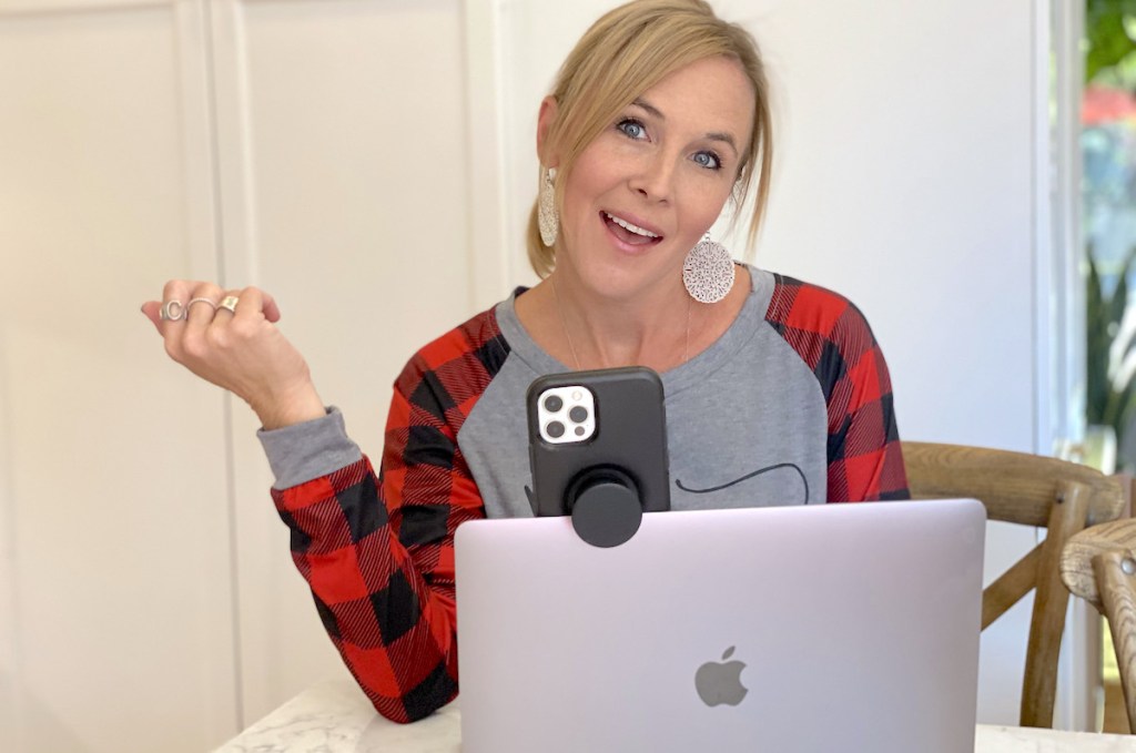 woman sitting in front of laptop with iphone hanging from top 