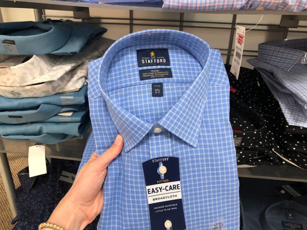 hand holding men's dress shirt in store