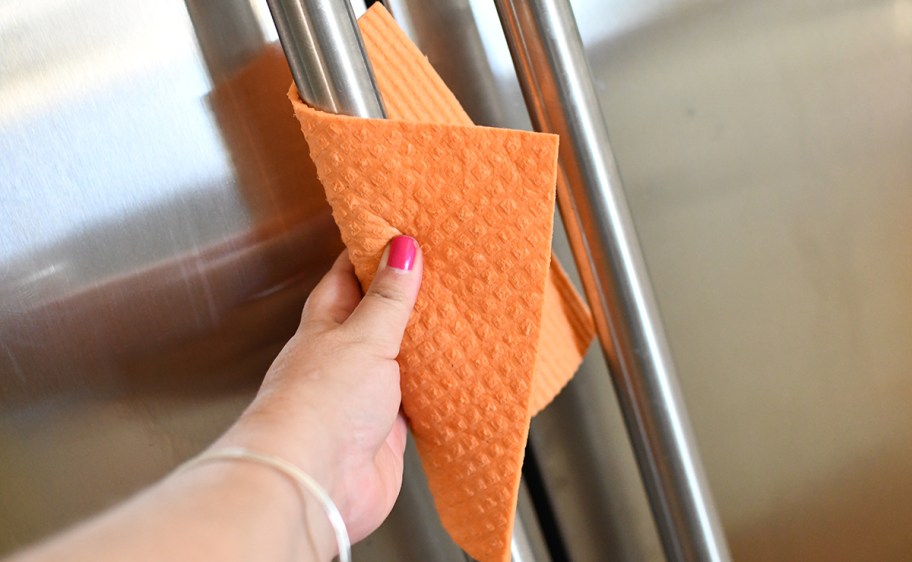 cleaning a stainless steel refrigerator with an orange cloth