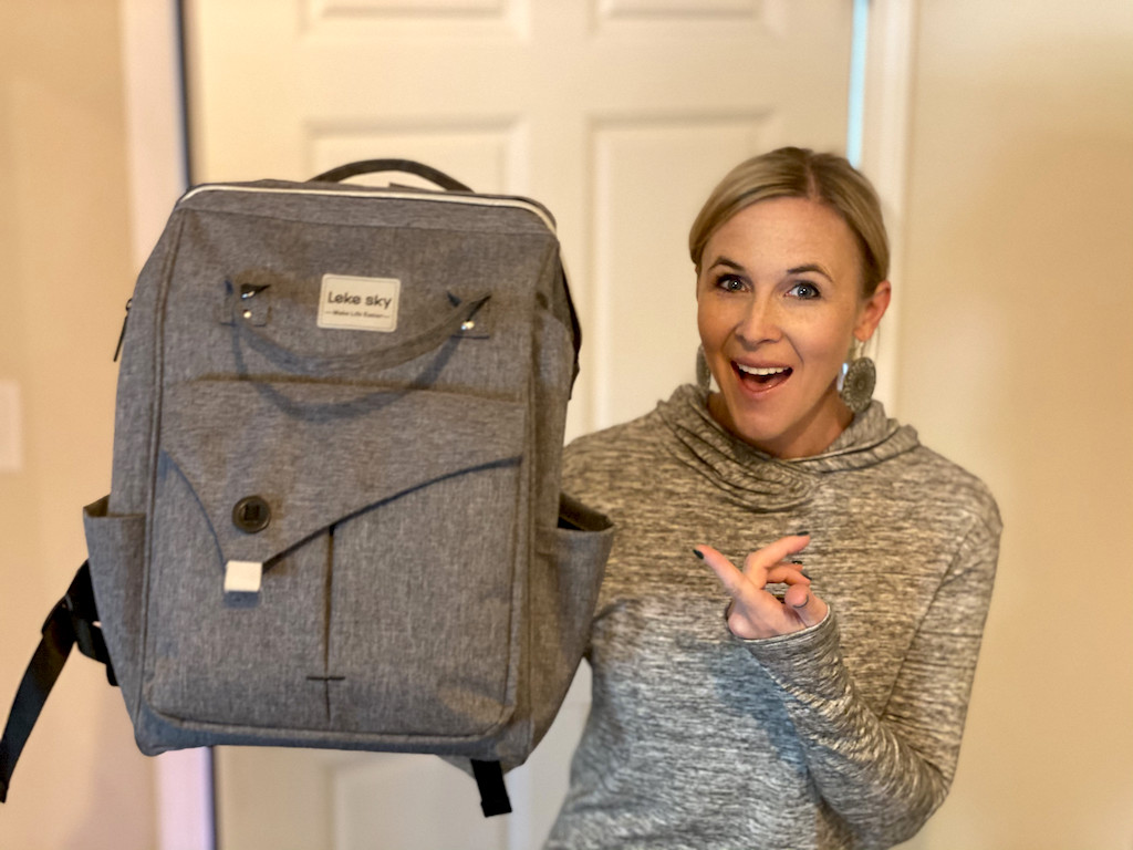 woman holding and pointing at grey travel backpack