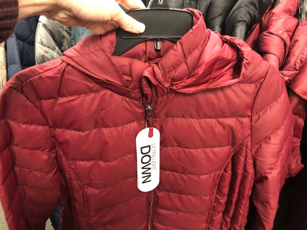 hand holding red jacket on hanger in store