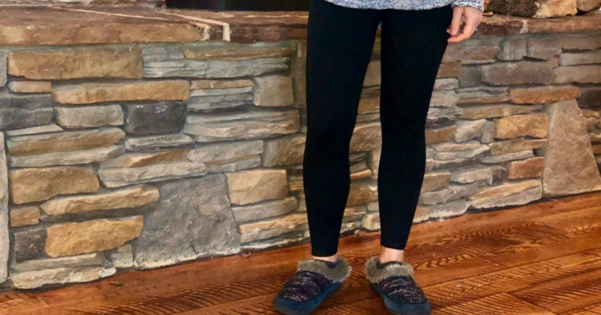 woman wearing black leggings and slippers in front of stone wall