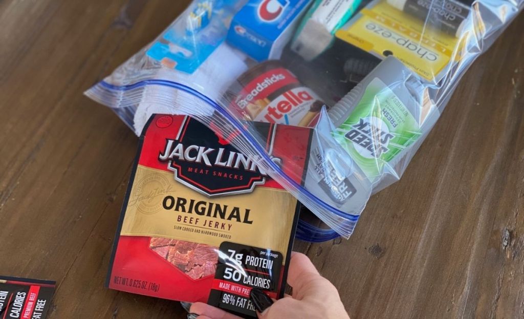 A hand placing some beef jerky in a freezer bag