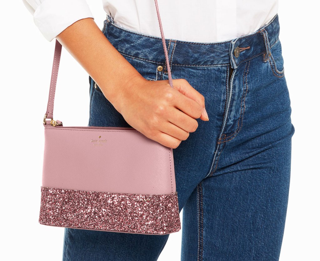 woman in high wasited jeans with a pink kate spade crossbody with pink sparkles at the bottom