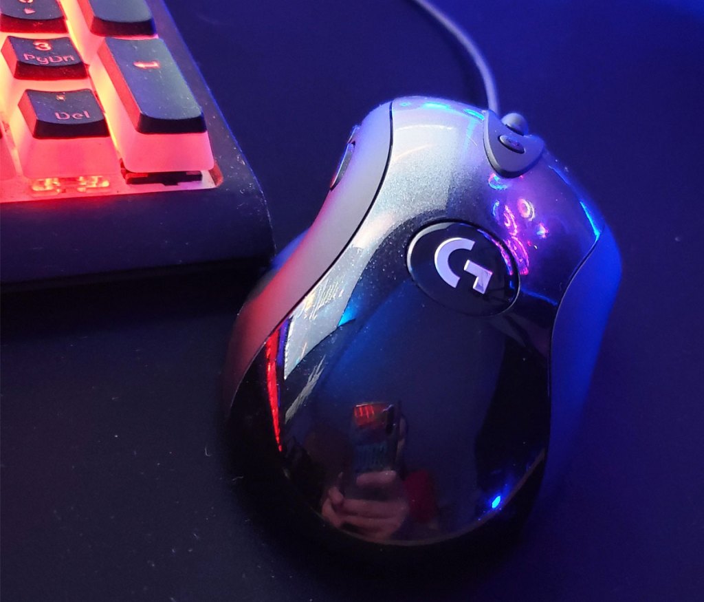 black logitech mouse on a black mousepad near an rgb gaming keyboard