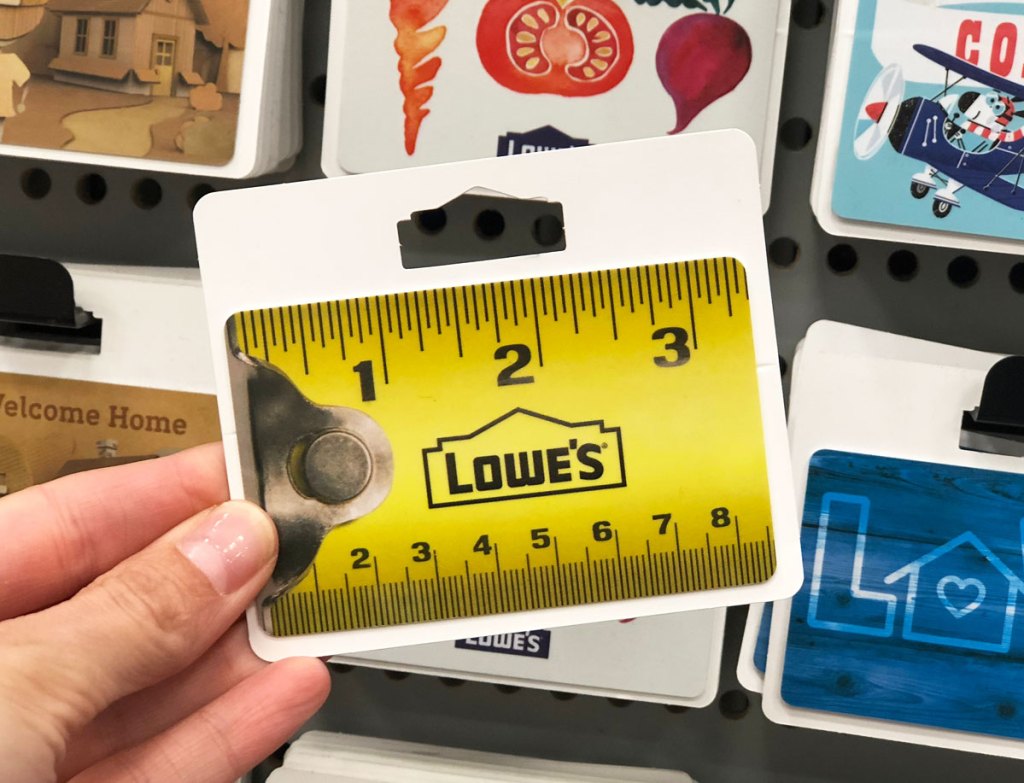 person holding up a lowe's gift card that looks like a measuring tape