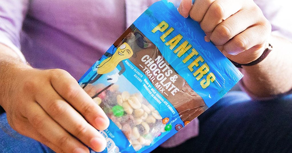 man holding a blue bag of planters trail mix in both hands