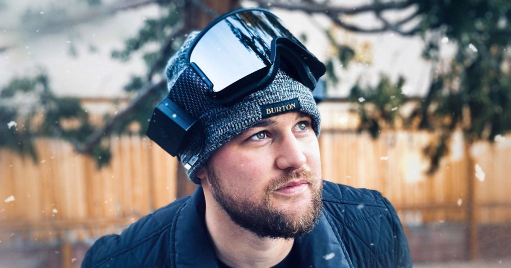 man standing outside in a black jacket with a grey beanie and black pair of ski goggles on top of his head
