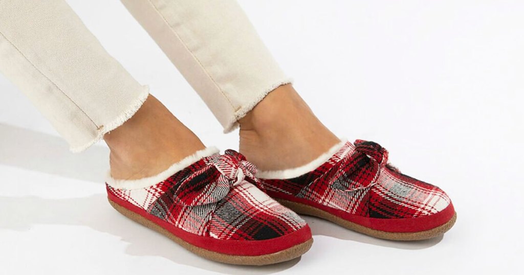 woman in cream colored skinny jeans with pair of red plaid slippers on her feet with matching bows on top