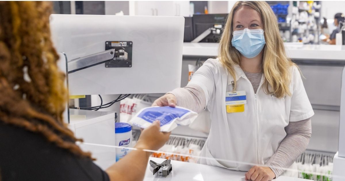 Walmart pharmacist handing bag to woman