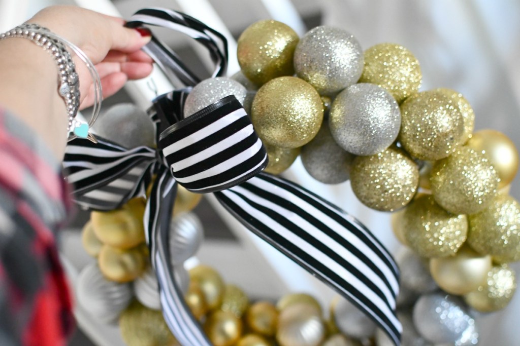 holding a ball ornament wreath with black and white ribbon