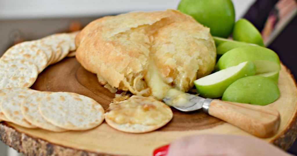 holding a tray with melted puff pastry baked brie