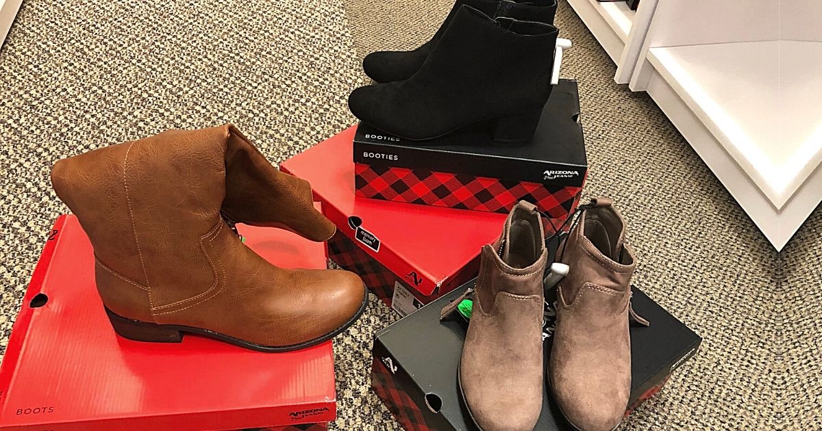 three pairs of womens boots sitting on boxes in a store