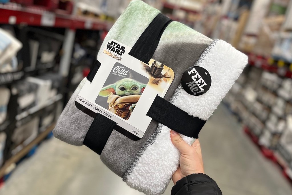 hand holding star ward throw blanket tied up with ribbon in store aisle