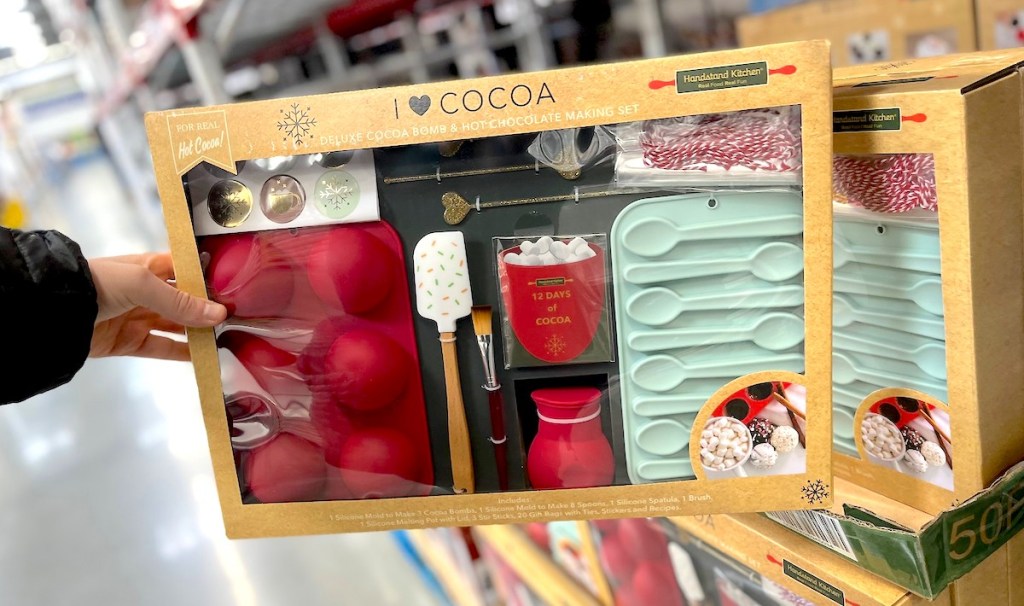 hand holding box of hot cocoa bomb kit essentials in store aisle