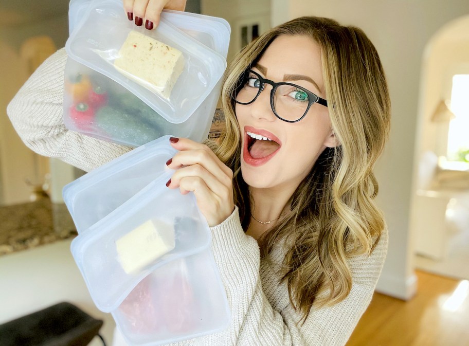 woman holding up various sizes of clear reusable bags with food inside