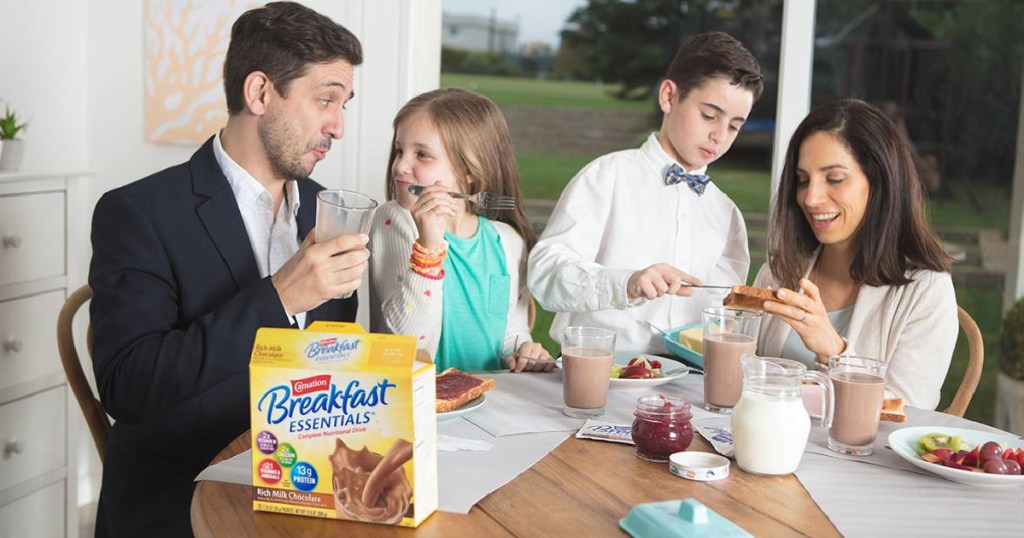 family sitting at table with a box of carnation breakfast essential
