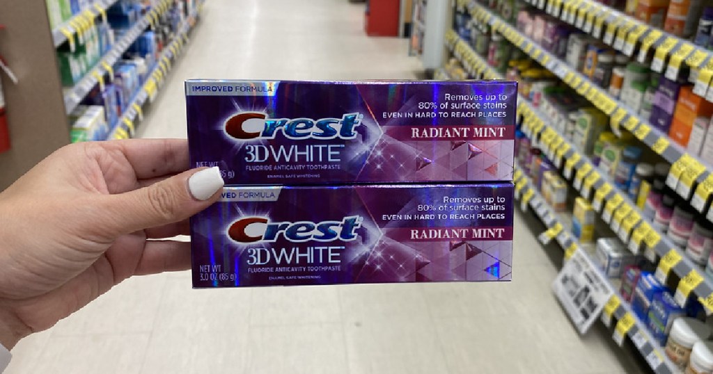 woman's hand holding two boxes of toothpaste in store