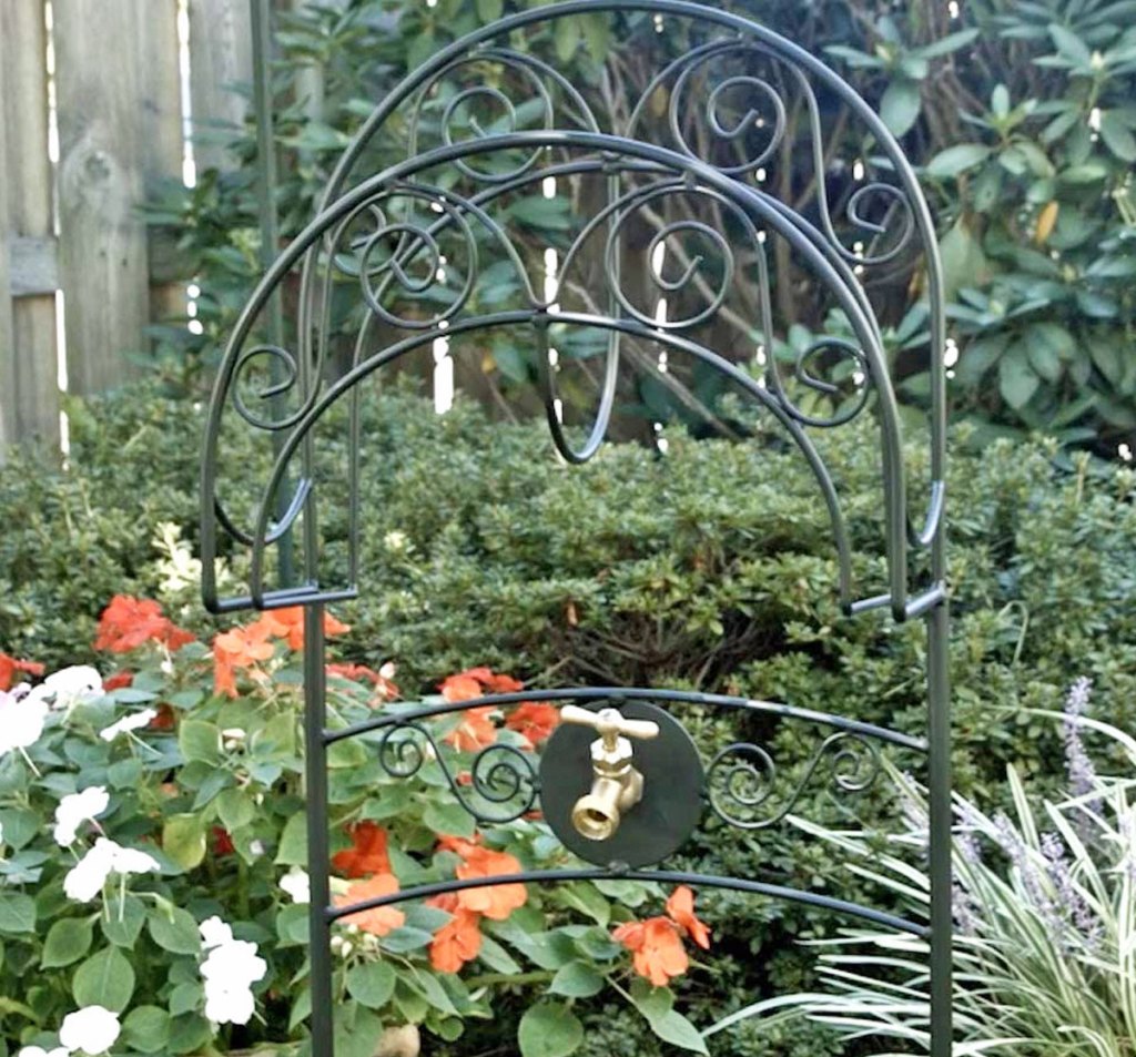 black metal garden hose stand placed in a garden