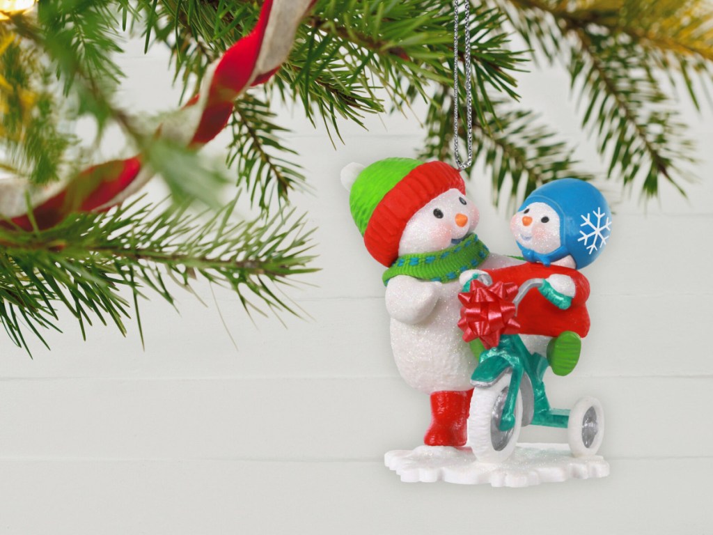 two snowmen standing next to each other one riding a trike