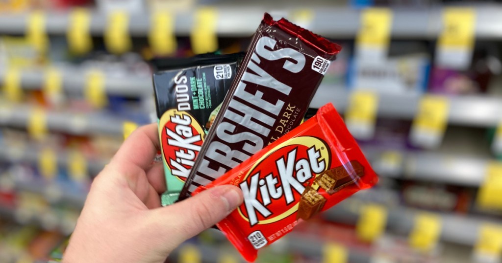 hand holding 3 hershey's candy bars at walgreens