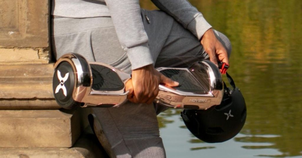 person in gray sweats holding Hover-1 Matrix Rose Gold Hover Board