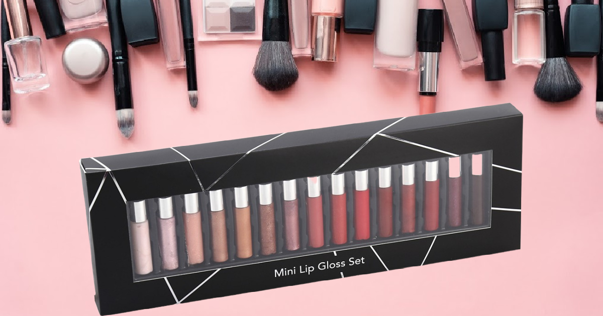 mini lip gloss set and various makeup brushes and beauty items on pink background