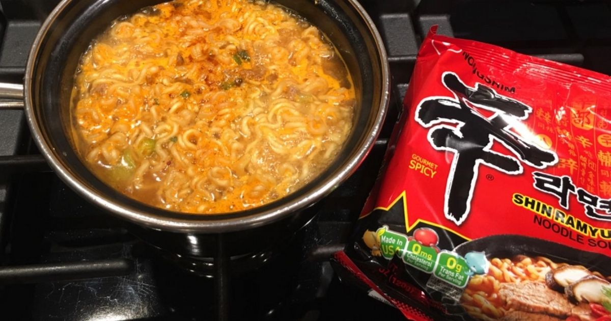 noodle soup cooking on a stovetop in a pot next to the soup packaging