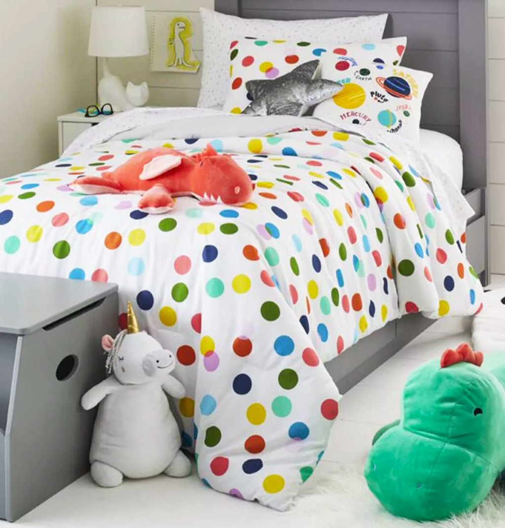 white comforter with multi-colored polka dot print on a kids bed