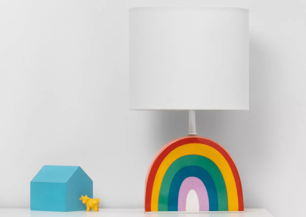 lamp with a rainbow base on a table by toys