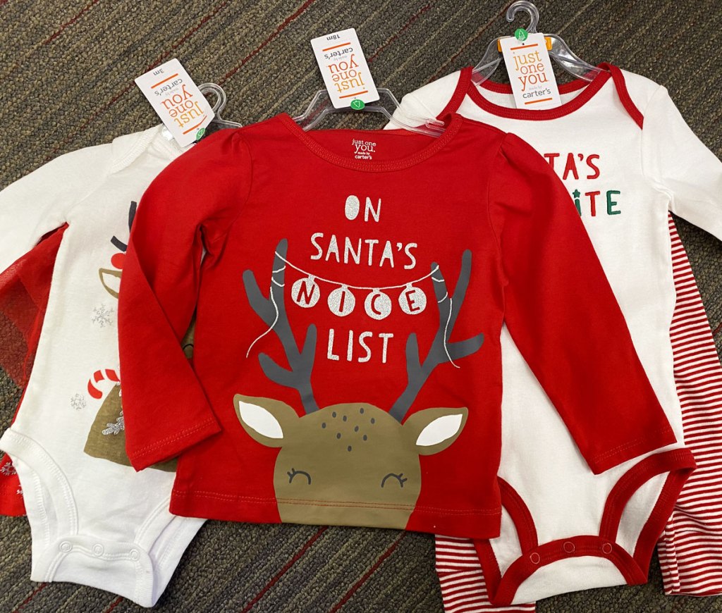 three pieces of carter's holiday baby apparel laid out on store floor