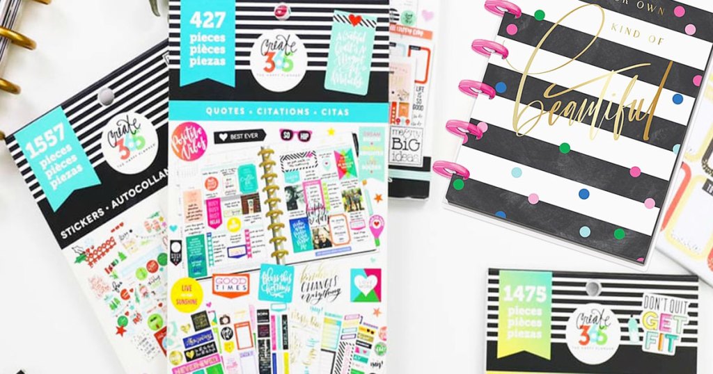 the happy planner sticker sheets and striped notebook on a table