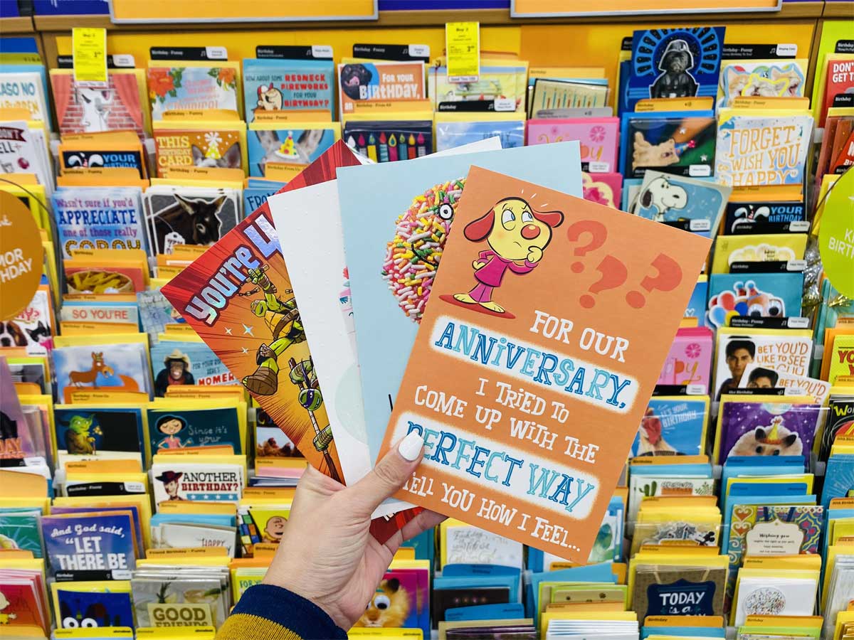 hand holding up four greeting cards in store