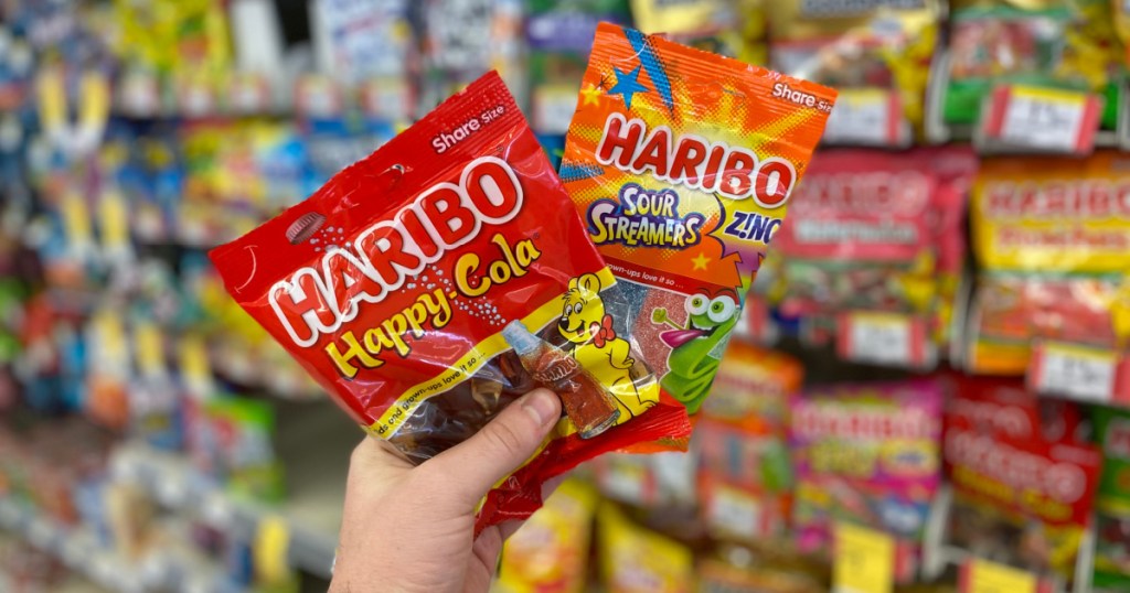 hand holding packs of haribo happy cola and sour streamers