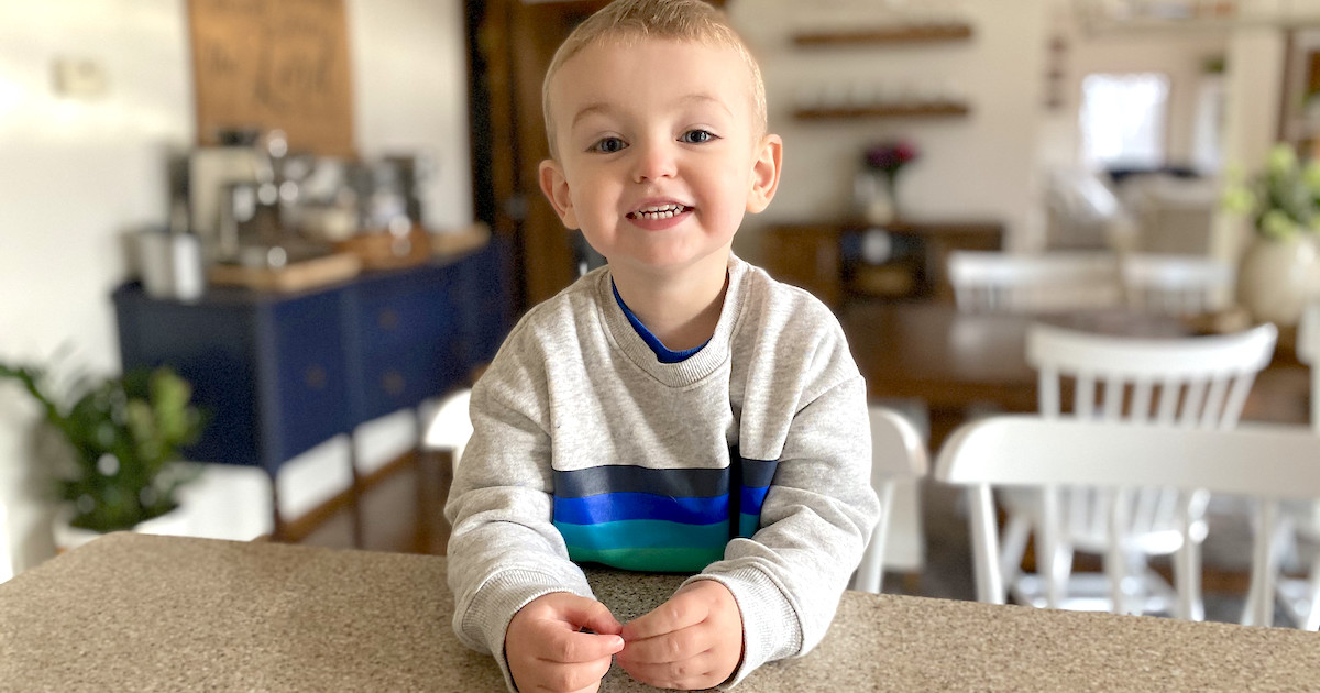 boy sitting at countertop wearing blue and green stripe sweatshirt