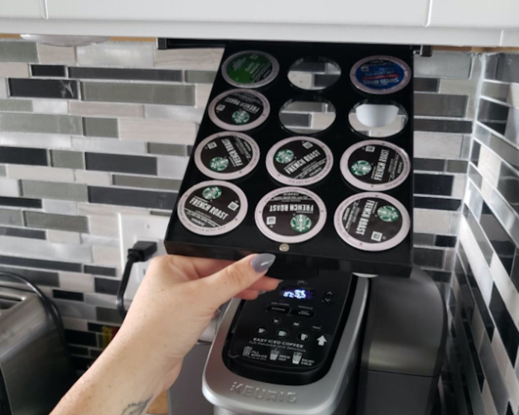 hand holding up k-cup organizer below kitchen cabinet