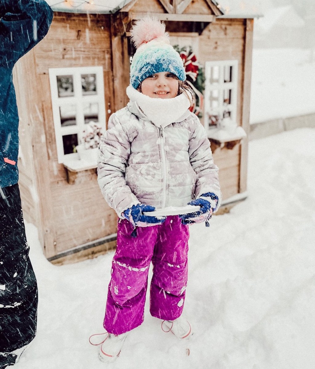 girl wearing winter gear outside in snow