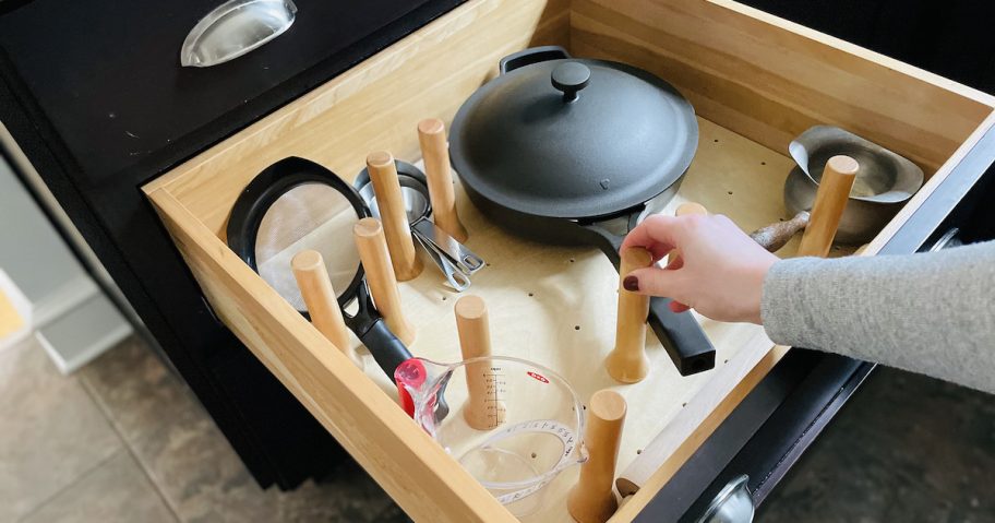 hand holding peg on wooden kitchen drawer peg board organizer