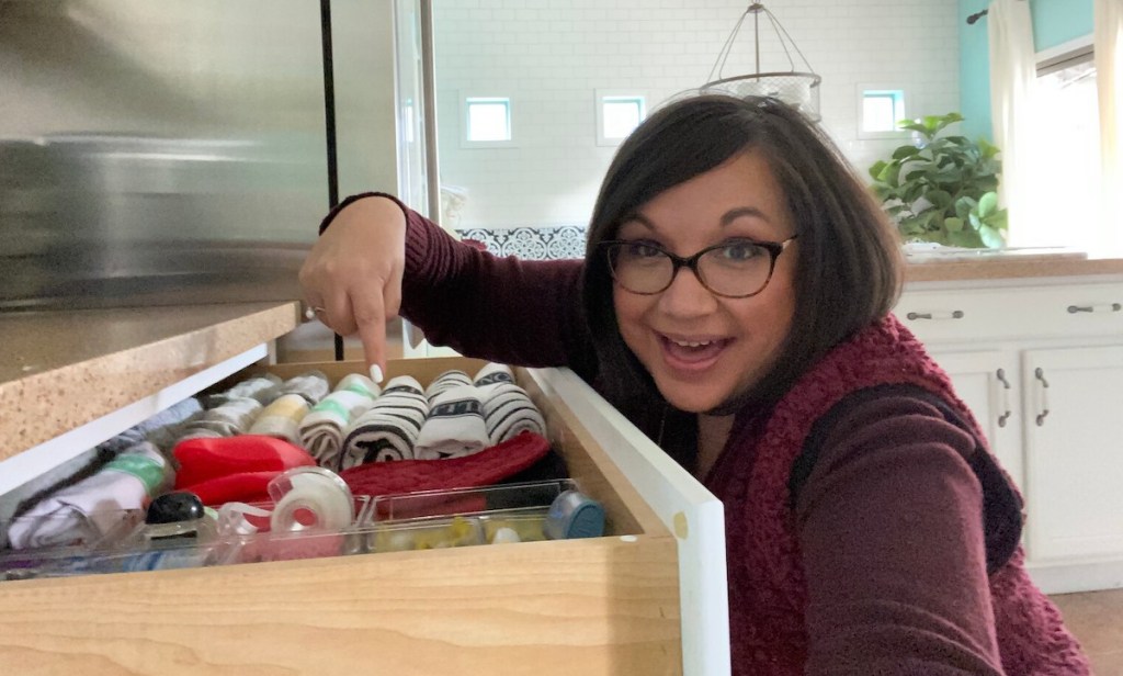 woman pointing inside organized junk drawer