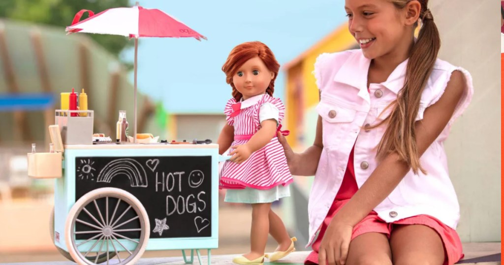 girl playing with our generation doll and hot dog cart