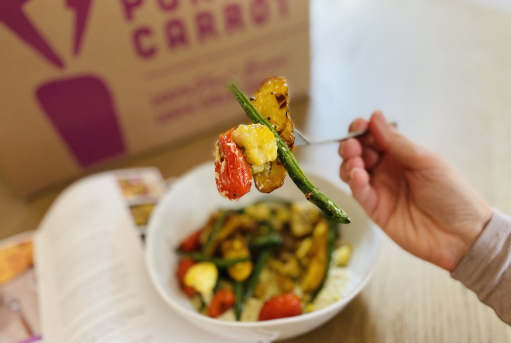 hand holding fork with cooked potatoes and vegetables on it