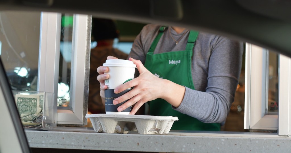 starbucks barista putting cup in travel carrier in drive thru