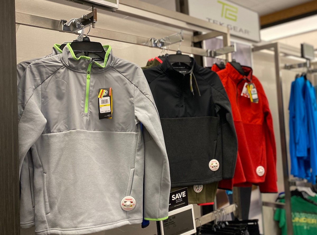 row of gray black red boys tek gear sweatshirts hanging up in store