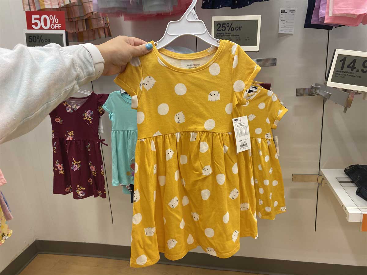 hand holding up a girls yellow dress in store