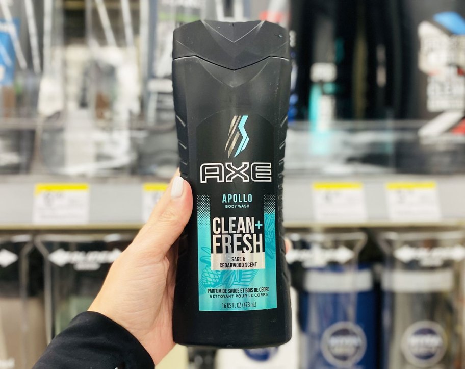 person holding up black bottle of axe body wash
