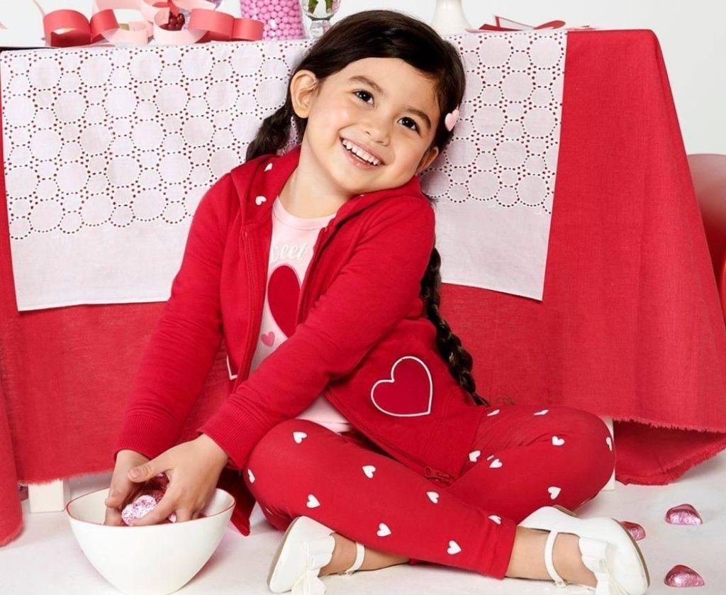 Little girl dressed in Valentine Theme clothing with bowl of heart shaped cadies