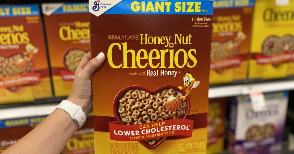 woman's handholding a large box of honey nut cheerios