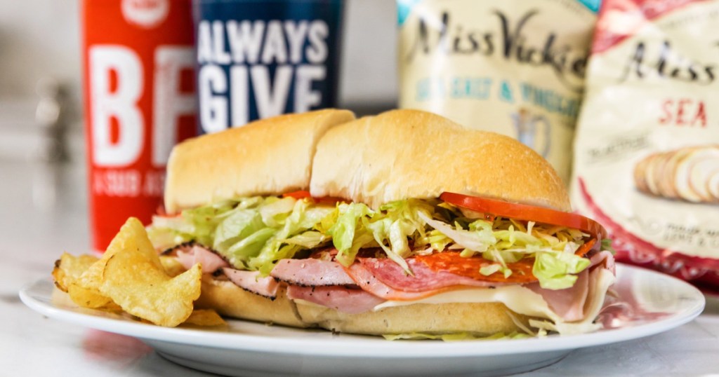 plate with sandwich on it and chips/drinks in the background